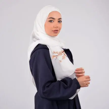 Hijab brodé en crêpe avec des fleurs dorées, signée Belle et Voilée by Nisreen, alliant élégance, finesse et qualité exceptionnelle. Fabrication syrienne. Dimensions : 65 x 180 cm