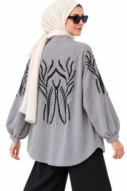 Femme voilée portant un cardigan long gris brodé à sequins noirs et argentés, vue trois-quarts