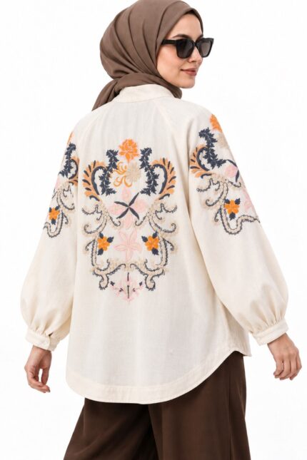 Cardigan long beige clair, avec broderies florales colorées, porté par une femme voilée, vue trois-quarts dos