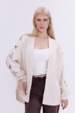 كارديغان طويل من الدنيم البيج المطرّز، مع تطريزات راقية وتفاصيل مرصّعة بالخرز.