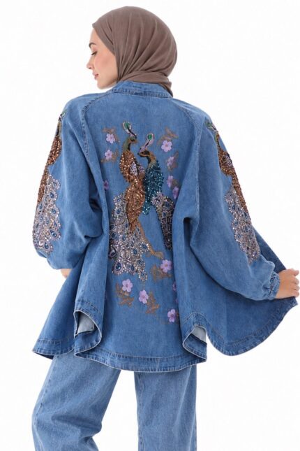 Cardigan long en jean bleu brodé, avec broderies de paons et fleurs, porté par une femme voilée vue de dos