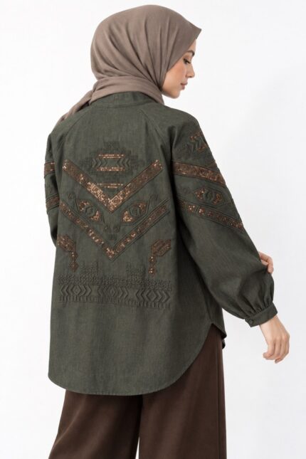 cardigan long en jean vert olive brodé, avec broderies cuivrées géométriques, porté par une femme voilée, vue de dos.