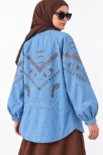 cardigan long en jean bleu clair brodé, avec broderies cuivrées géométriques, porté par une femme voilée, vue de dos.