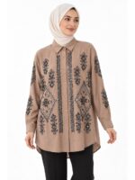 A long, beige embroidered tunic, seen from the front on a veiled model, featuring geometric patterns and sequins on the front and sleeves.